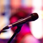 Close-up shot of a microphone on stage with colorful background bokeh, capturing live performance ambiance.
