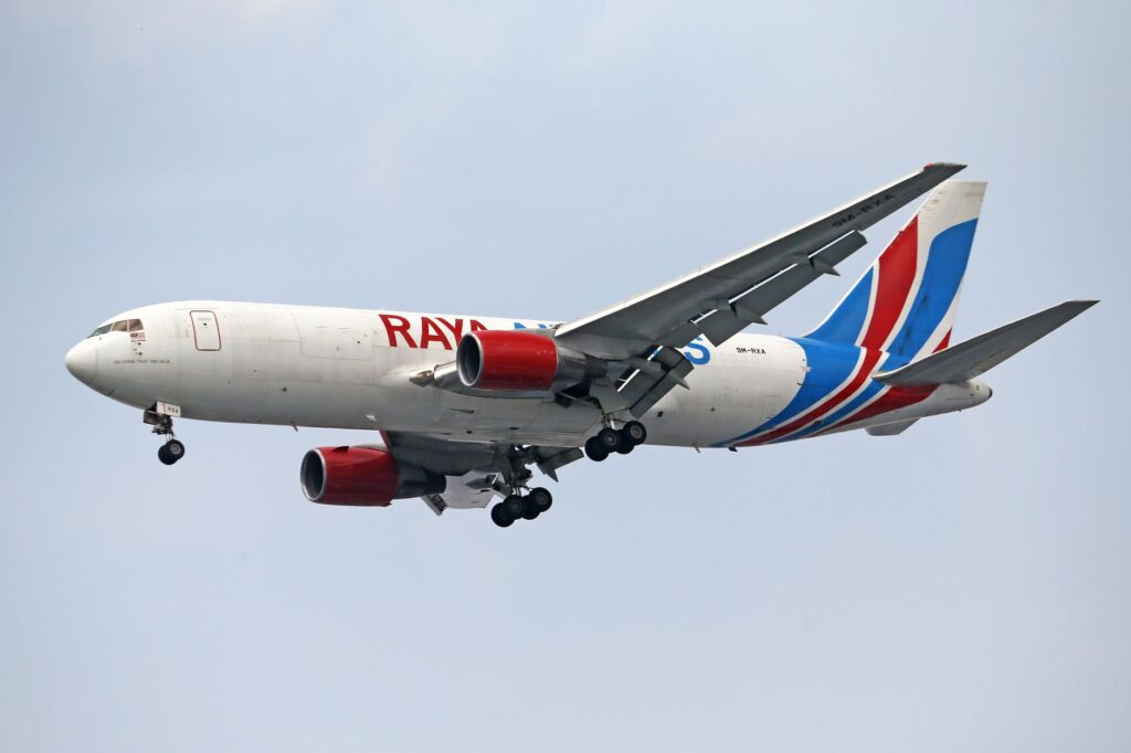 Close-up of a cargo airplane flying in a clear blue sky, showcasing vibrant colors and design.