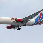 Close-up of a cargo airplane flying in a clear blue sky, showcasing vibrant colors and design.