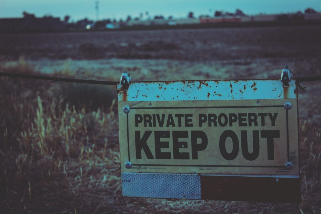 Private property sign with keep out warning in Atwater, California field.