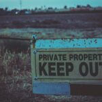 Private property sign with keep out warning in Atwater, California field.