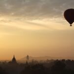Hot air balloon gracefully glides over Bagan temples at sunrise, capturing serene adventure.