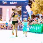 A joyful mother and daughter cross the marathon finish line hand in hand, exuding happiness and energy.