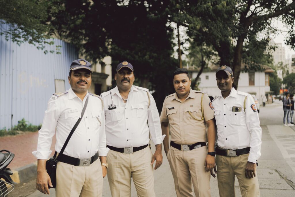 Four policemen in uniform standing on a street in Mumbai, India.