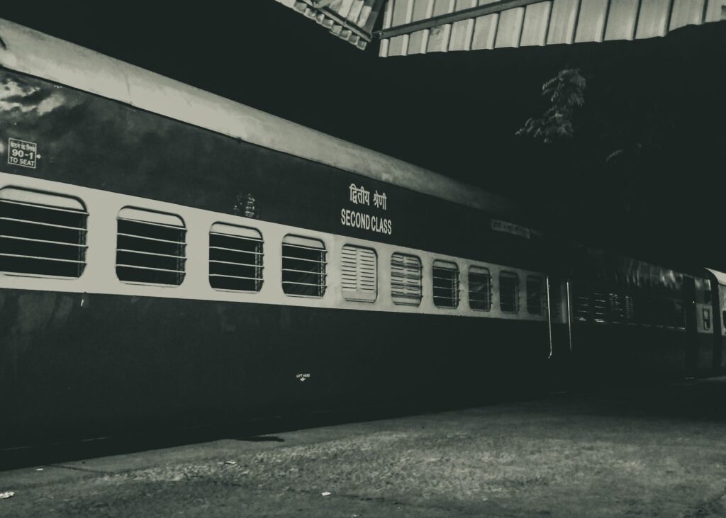 Night photo of a second class train parked outdoors under a station roof.