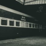 Night photo of a second class train parked outdoors under a station roof.