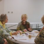 An intergenerational group of women engaged in a Bible study session indoors.