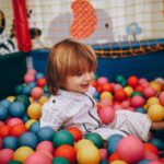 A cheerful child enjoying playtime in a colorful indoor ball pit.