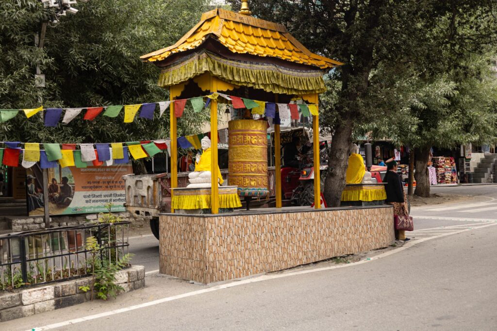 Large Buddhist prayer wheel with colorful flags in a peaceful outdoor setting, capturing local culture and spirituality.