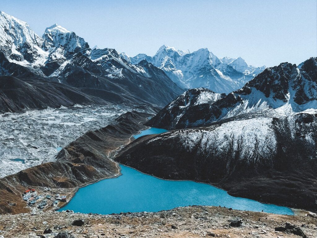 Stunning aerial view of snow-capped Himalayas and a turquoise lake in clear weather, Nepal.