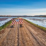 A road closed sign on a gravel path next to a flooded area in Kellogg, MN.