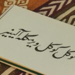 Notebook with Persian calligraphy on colorful patterned fabric background.