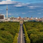 Stunning aerial view of Berlin's skyline with landmarks like Brandenburg Gate and Fernsehturm under blue sky.