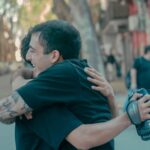 Two friends sharing a heartfelt embrace on a bustling Argentinian street.