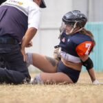 A female rugby player receives assistance from a medic on the field after an injury.
