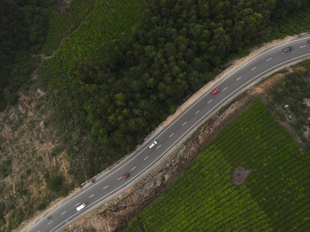 Drone shot of a winding road amid lush green tea plantations in Kannan Devan Hills, India.