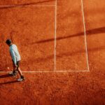 Tennis player practices on a sunny clay court in Buenos Aires, Argentina.