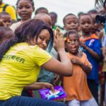 A vibrant scene of children and volunteers participating in an outdoor community outreach activity.