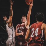 Players compete fiercely during a basketball game under stadium lights.