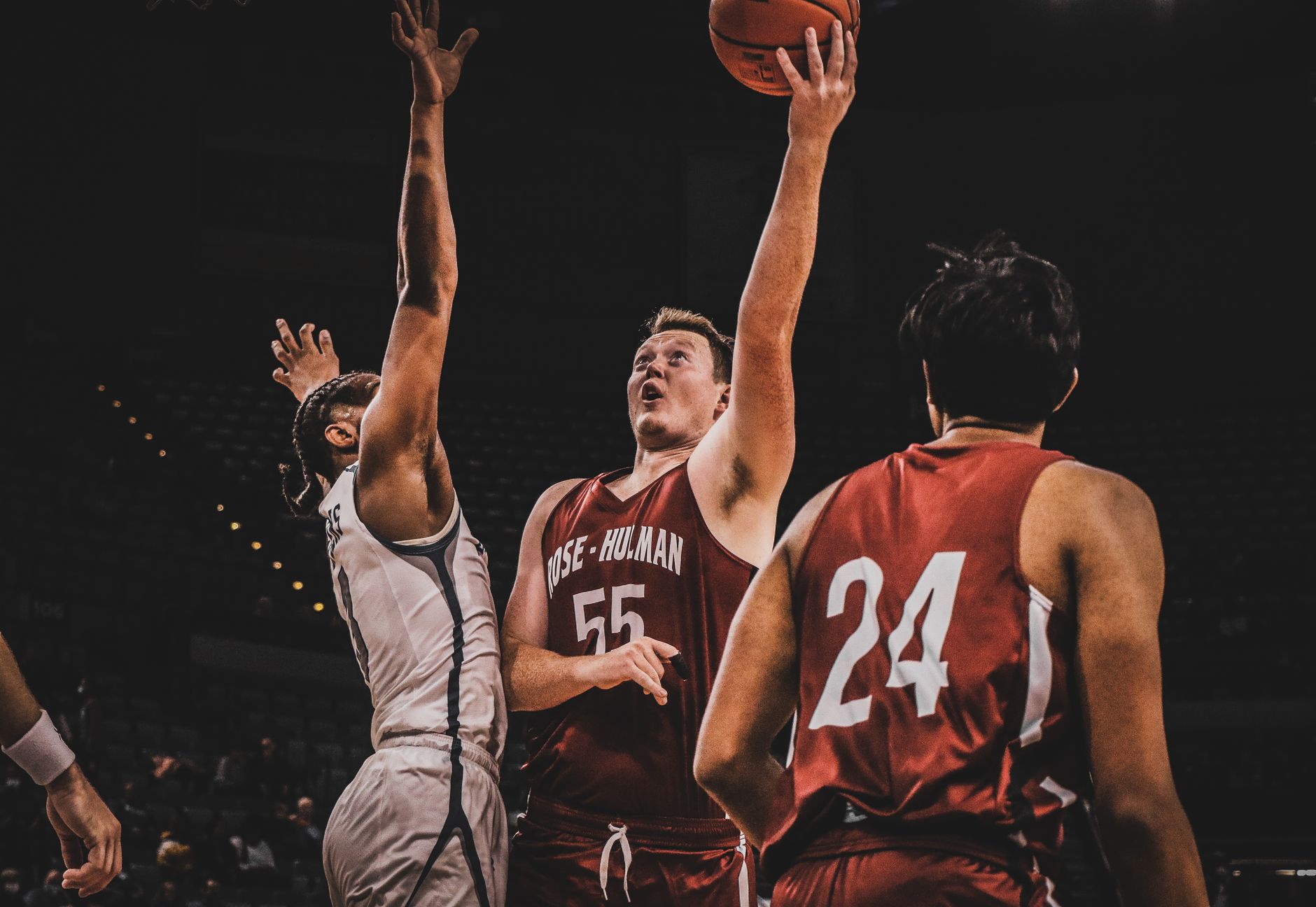Players compete fiercely during a basketball game under stadium lights.