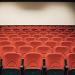 A spacious theater with empty red seats and a large screen, ready for the next audience.