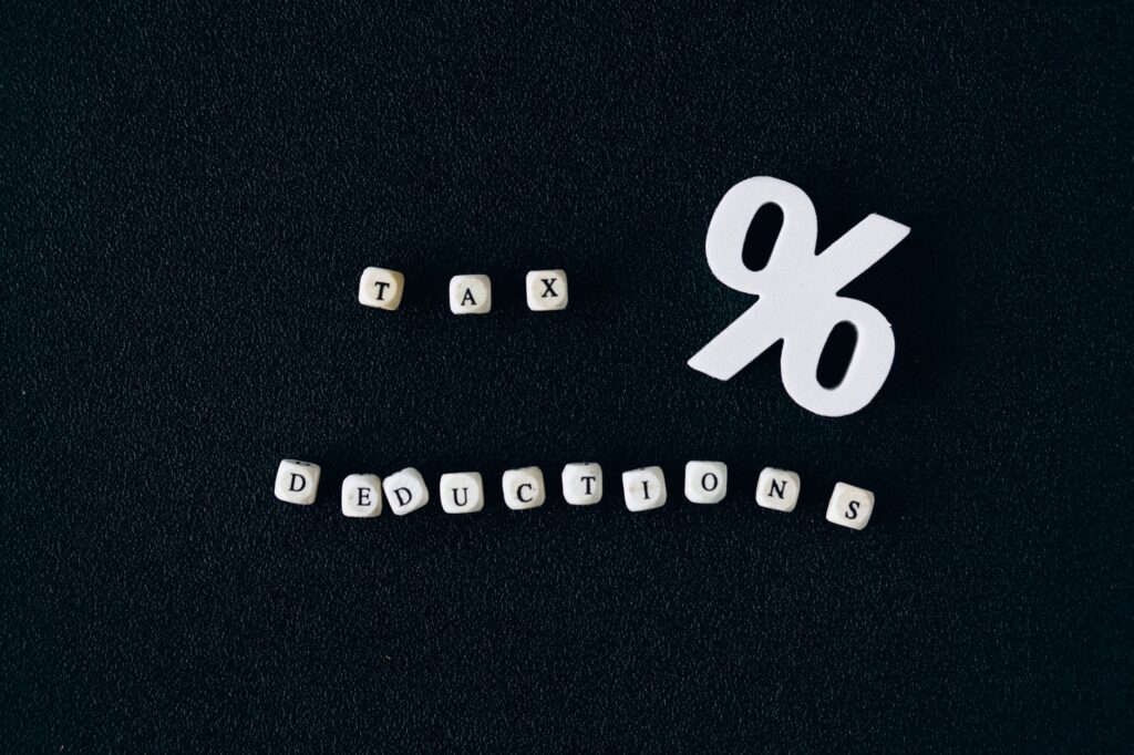 Conceptual image of tax deductions with alphabet blocks and percent symbol on black surface.
