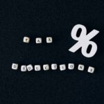 Conceptual image of tax deductions with alphabet blocks and percent symbol on black surface.