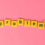Yellow letter tiles spelling 'problems' on a contrasting pink background. Perfect for creative design projects.