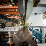Interior view of an industrial building featuring machinery and metal conveyor systems.