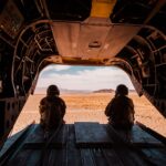 Soldiers seated in helicopter looking over a vast desert landscape.