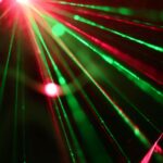 Dynamic display of red and green laser lights creating vivid rays across a dark background.