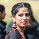 Portrait of a woman wearing ornate Indian jewelry, captured outdoors in a bright setting.