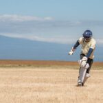 A cricket player batting outdoors on a sunny day, showcasing athletic skill.