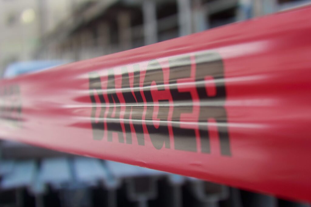 Focused close-up of red danger barricade tape at a construction site.