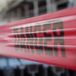 Focused close-up of red danger barricade tape at a construction site.
