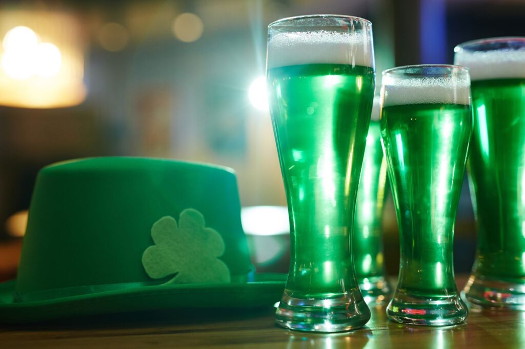 Vibrant green beers and shamrock hat symbolize a cheerful Saint Patrick's Day celebration indoors.
