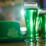 Vibrant green beers and shamrock hat symbolize a cheerful Saint Patrick's Day celebration indoors.