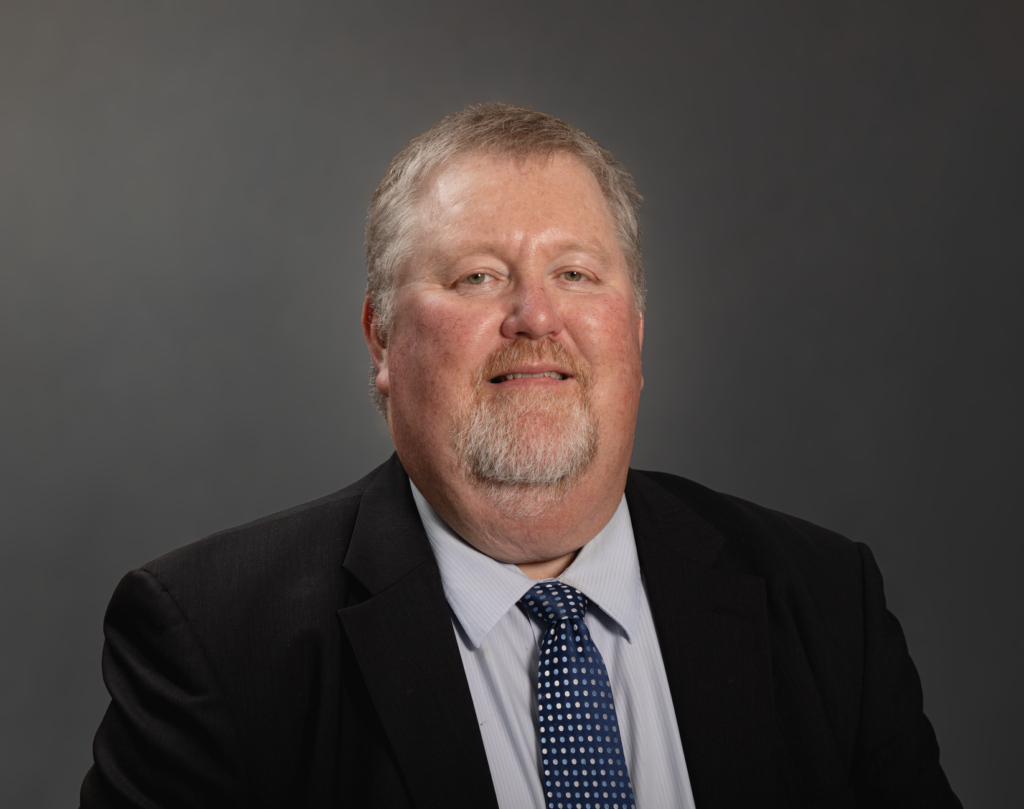 Portrait of a businessman in formal attire against a neutral background.