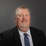 Portrait of a businessman in formal attire against a neutral background.
