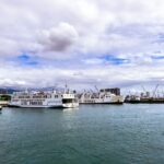 Ferry boats docked at a bustling harbor in Cebu City, under a partly cloudy sky.
