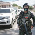 A Philippine soldier in uniform and mask standing on a city street, showcasing military presence.