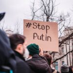 People in Berlin protest against Putin with anti-war signs, showing unity for peace.