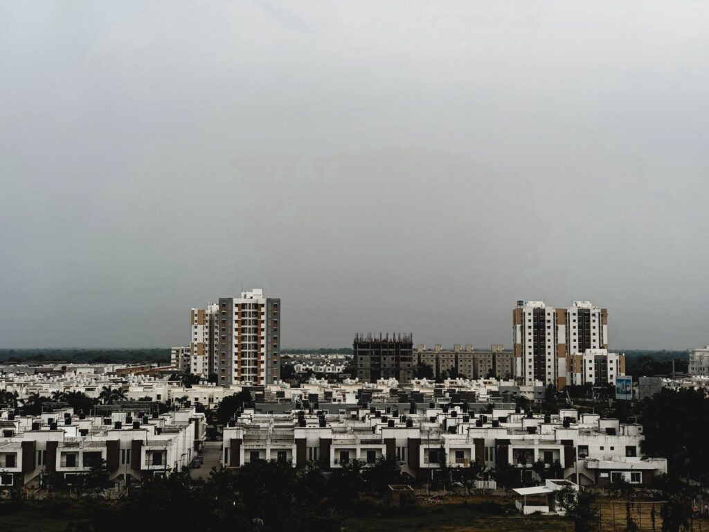 A view of urban residential and commercial buildings under an overcast sky in Vadodara, India.