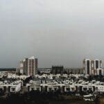 A view of urban residential and commercial buildings under an overcast sky in Vadodara, India.