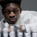 Focused young man playing chess, contemplating his next strategic move.