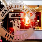 Close-up of Manchester United emblem etched on glass, showcasing iconic design indoors.