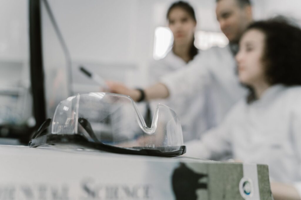 Scientists working in a lab, focused with protective goggles in the foreground.
