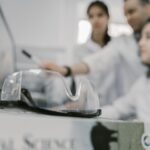 Scientists working in a lab, focused with protective goggles in the foreground.