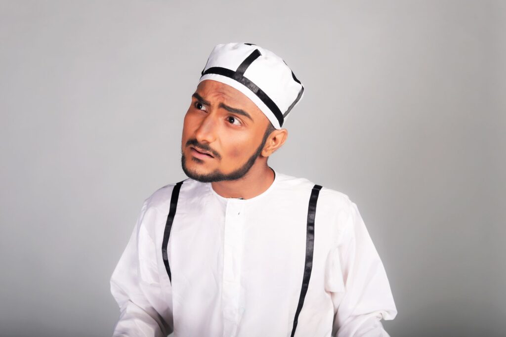 Portrait of a South Asian man in traditional attire with a curious expression. Studio shot.