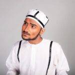 Portrait of a South Asian man in traditional attire with a curious expression. Studio shot.